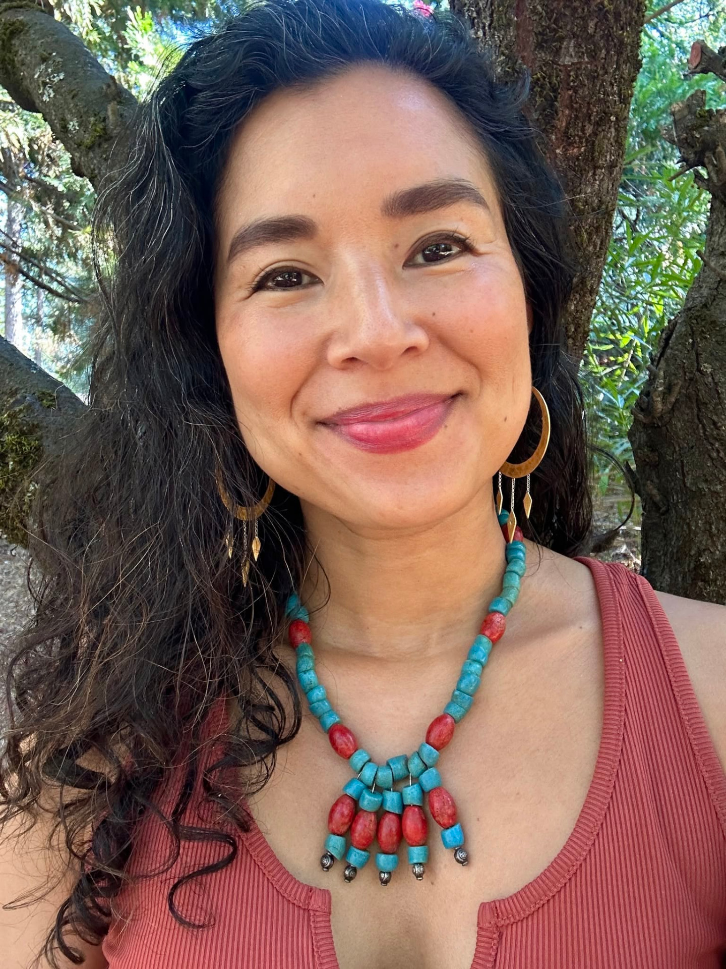 Aimi Colibrí, Jungian coach, smiling outdoors among trees