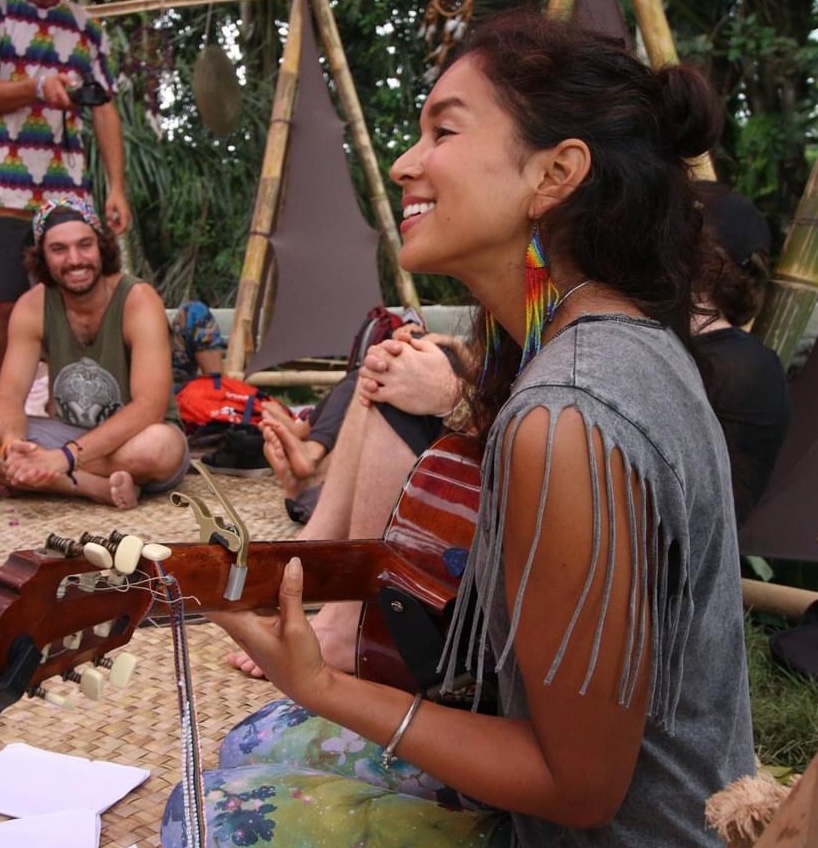 Aimi playing guitar and singing in a ceremony circle