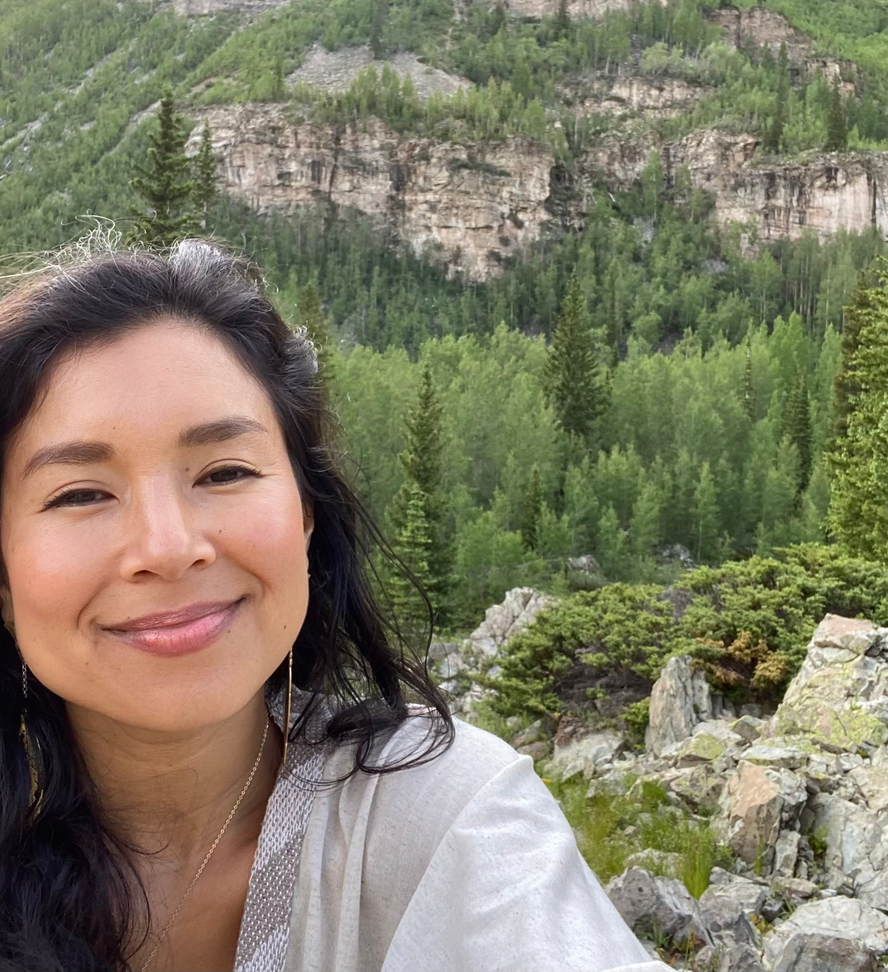 Aimi outdoors with mountains and forest behind her